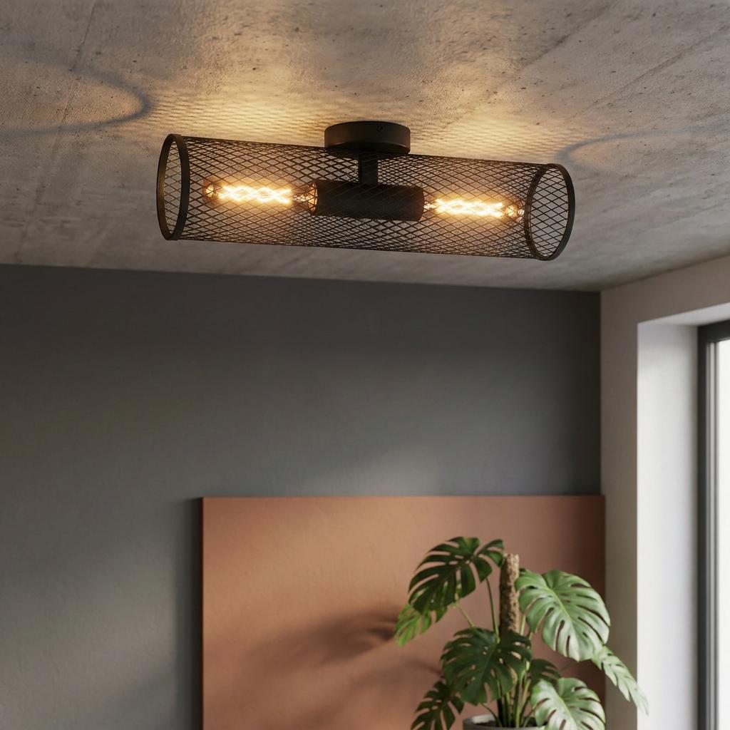 Industrial black mesh cylinder flush mount light with two glowing bulbs on a concrete ceiling.