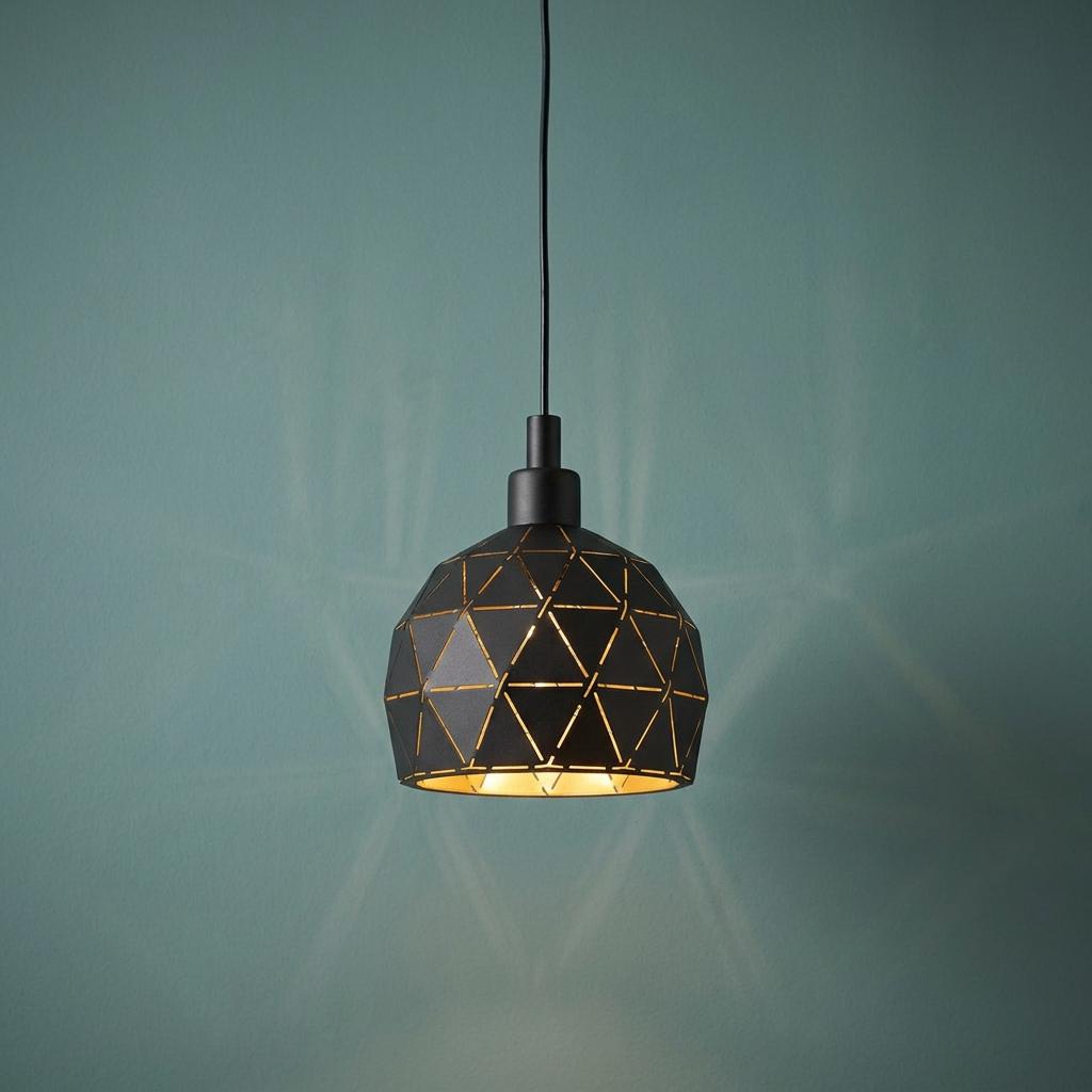 Black geometric dome pendant light with a gold interior glowing against a teal wall.