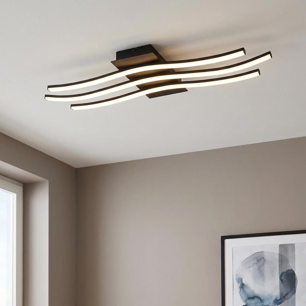 Modern black flush ceiling light with three curved LED bars glowing against a white ceiling in a neutral room.