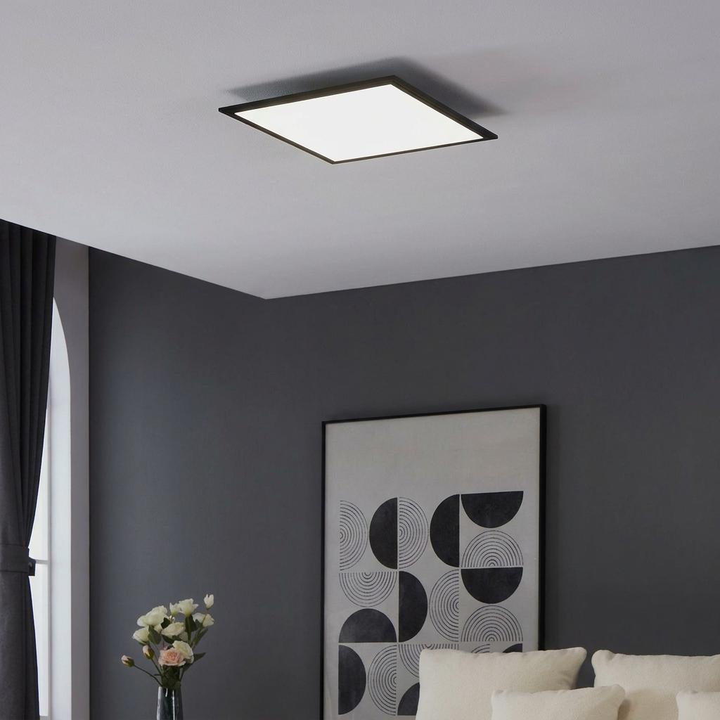 Modern square LED flush ceiling light with a black frame mounted on a white ceiling in a grey living room.