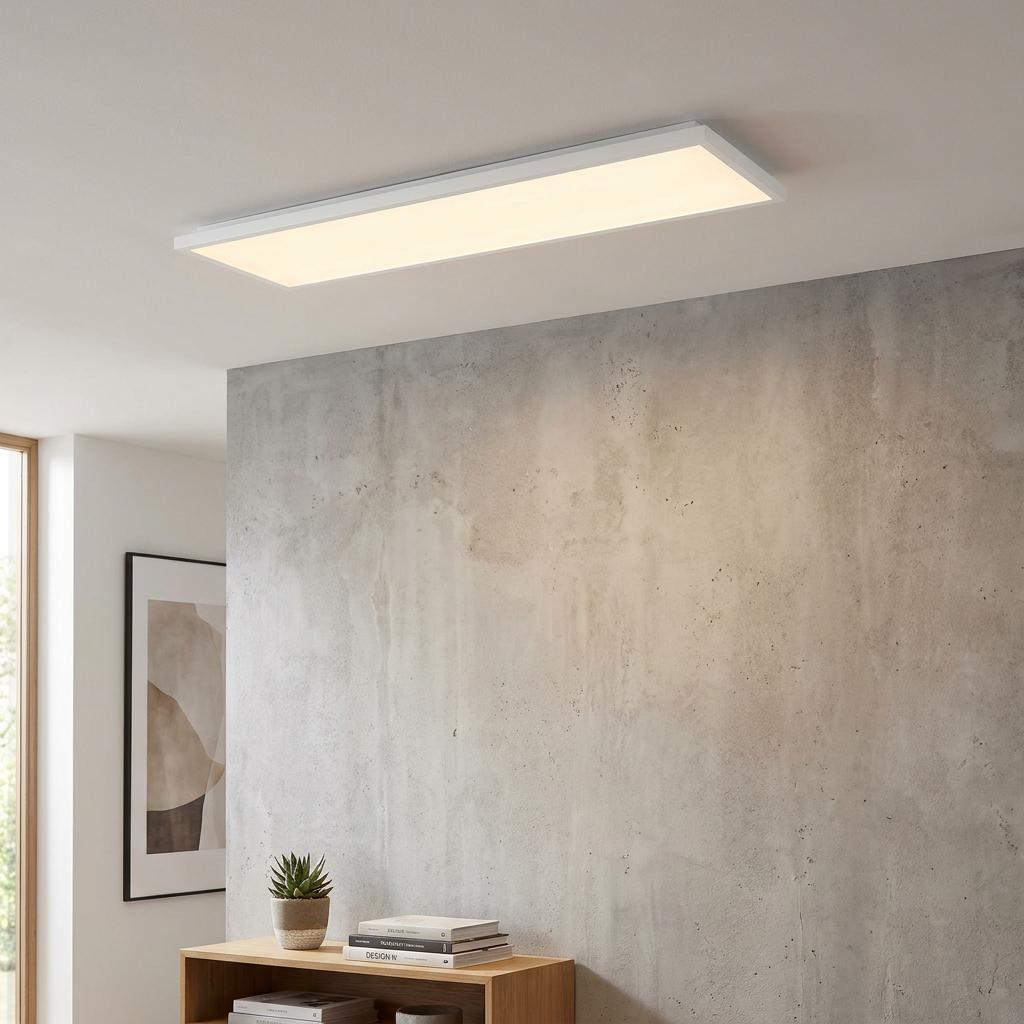 Slim rectangular white LED panel light flush-mounted to a white ceiling in a room with a concrete wall.