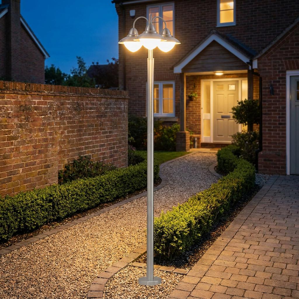 Eglo Sidney 3-light silver outdoor lamp post with opal glass shades illuminating a gravel pathway at night.