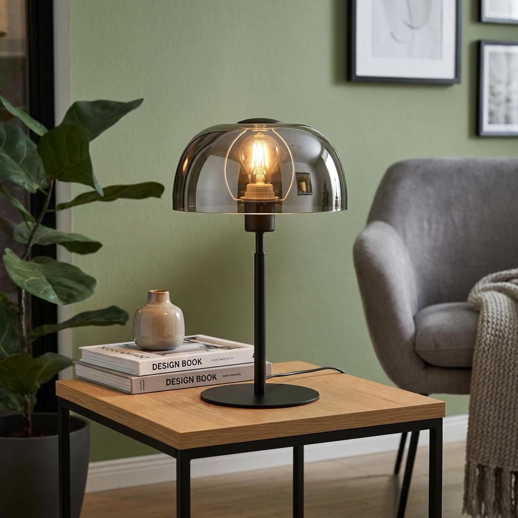 Lit black table lamp with a smoked glass dome shade on a wooden side table in a modern living room.