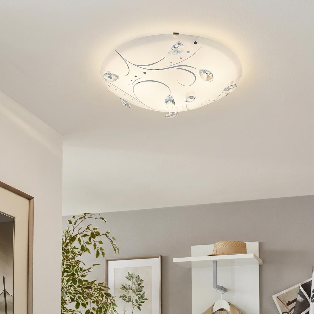 Eglo Sorrenta 1 white glass flush ceiling light with crystal accents and silver swirls mounted on a white ceiling.