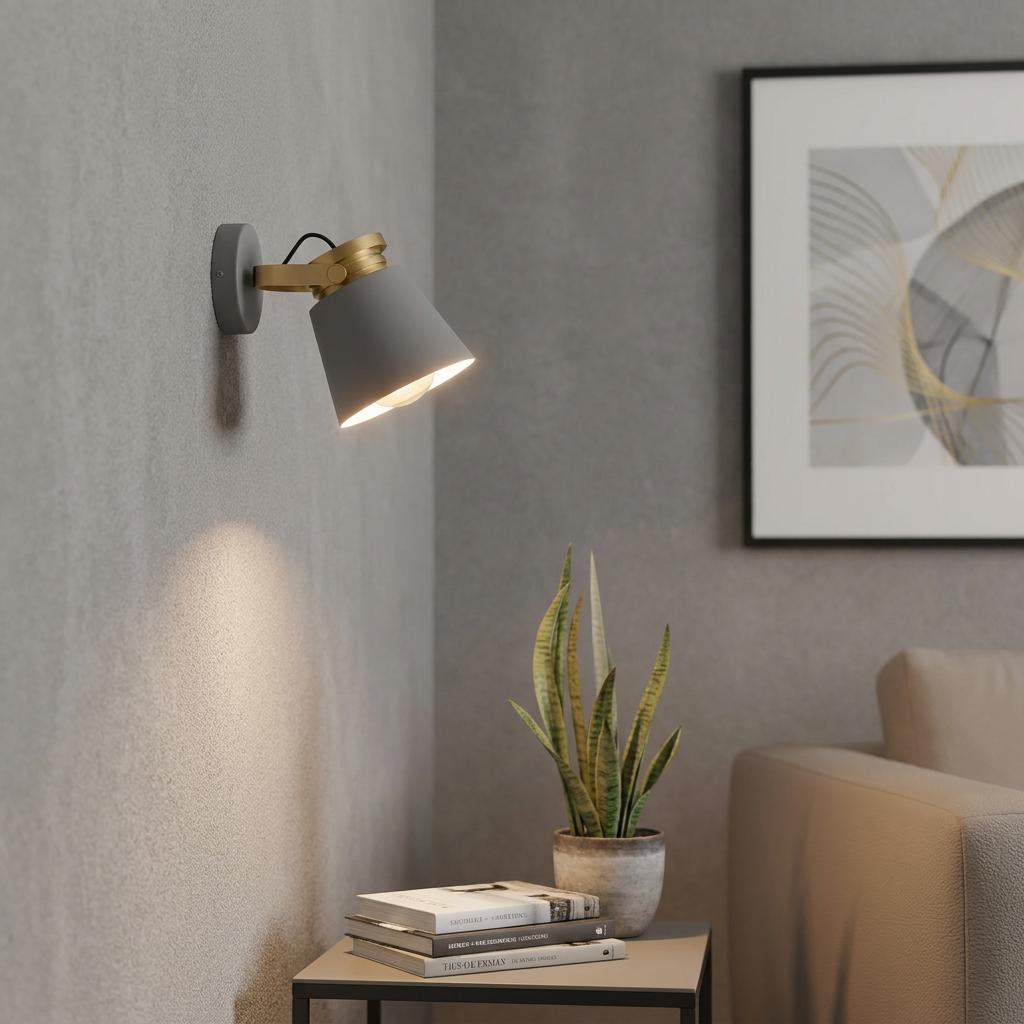 Modern grey and gold wall spotlight illuminating a side table with books and a plant against a textured wall.