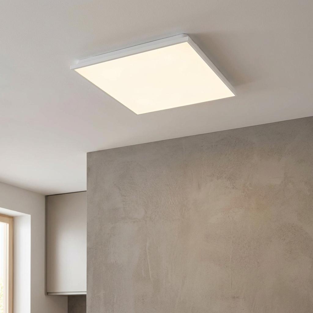 Square white LED panel flush ceiling light glowing in a modern room with a neutral textured wall.