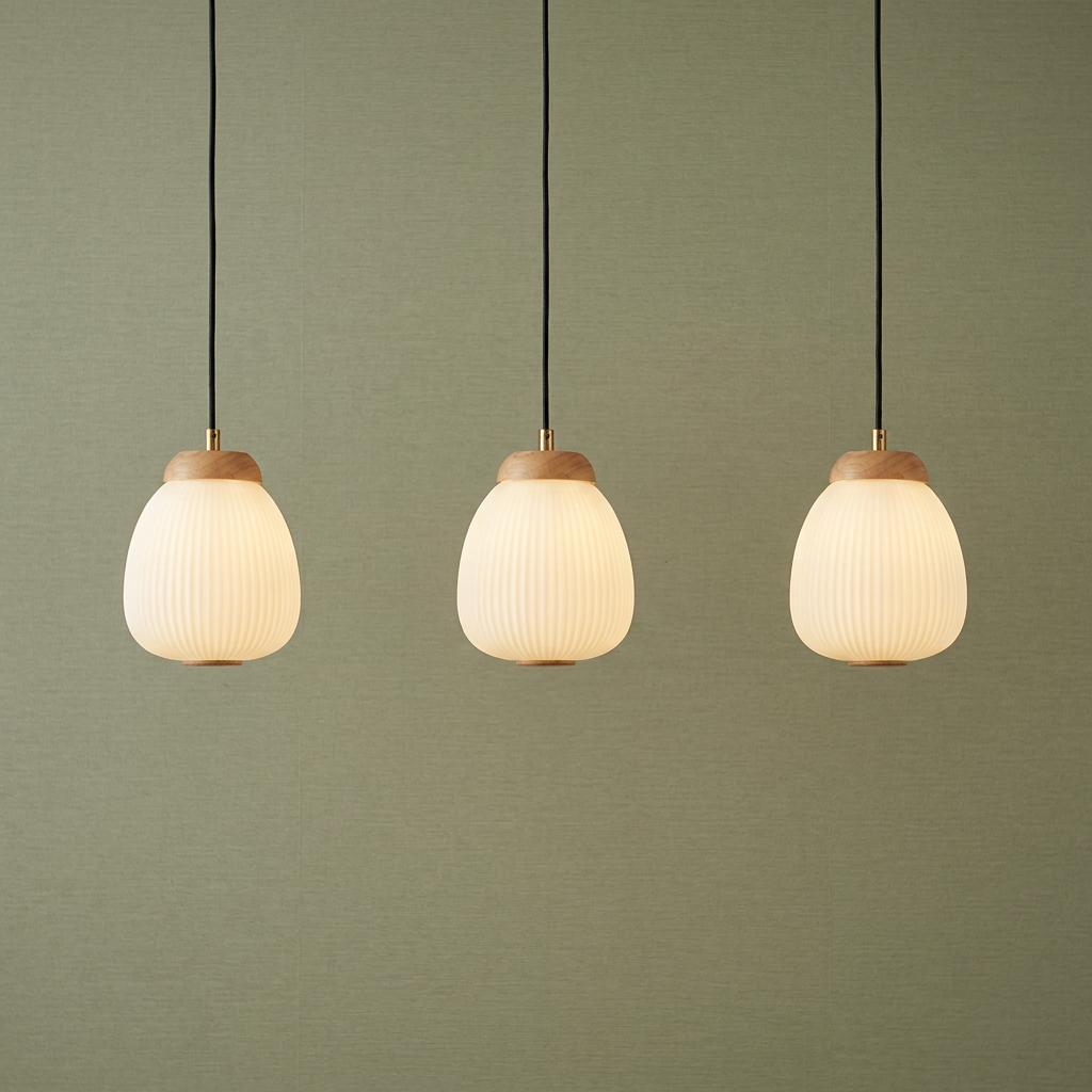 Three Ella pendant lights with ribbed opal glass shades and wooden tops hanging against a sage green textured wall.
