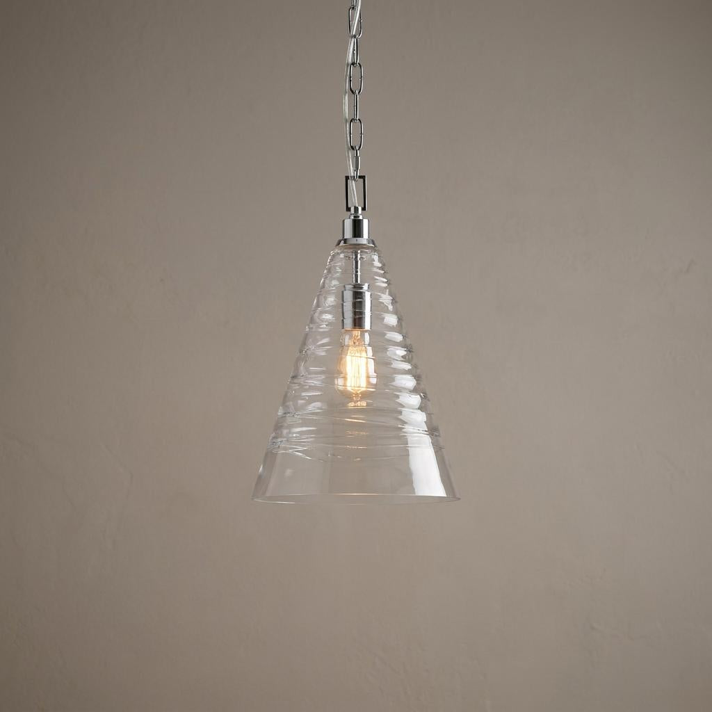 Elmore 1 Light Polished Chrome Pendant with a conical ribbed glass shade and glowing bulb against a neutral wall.