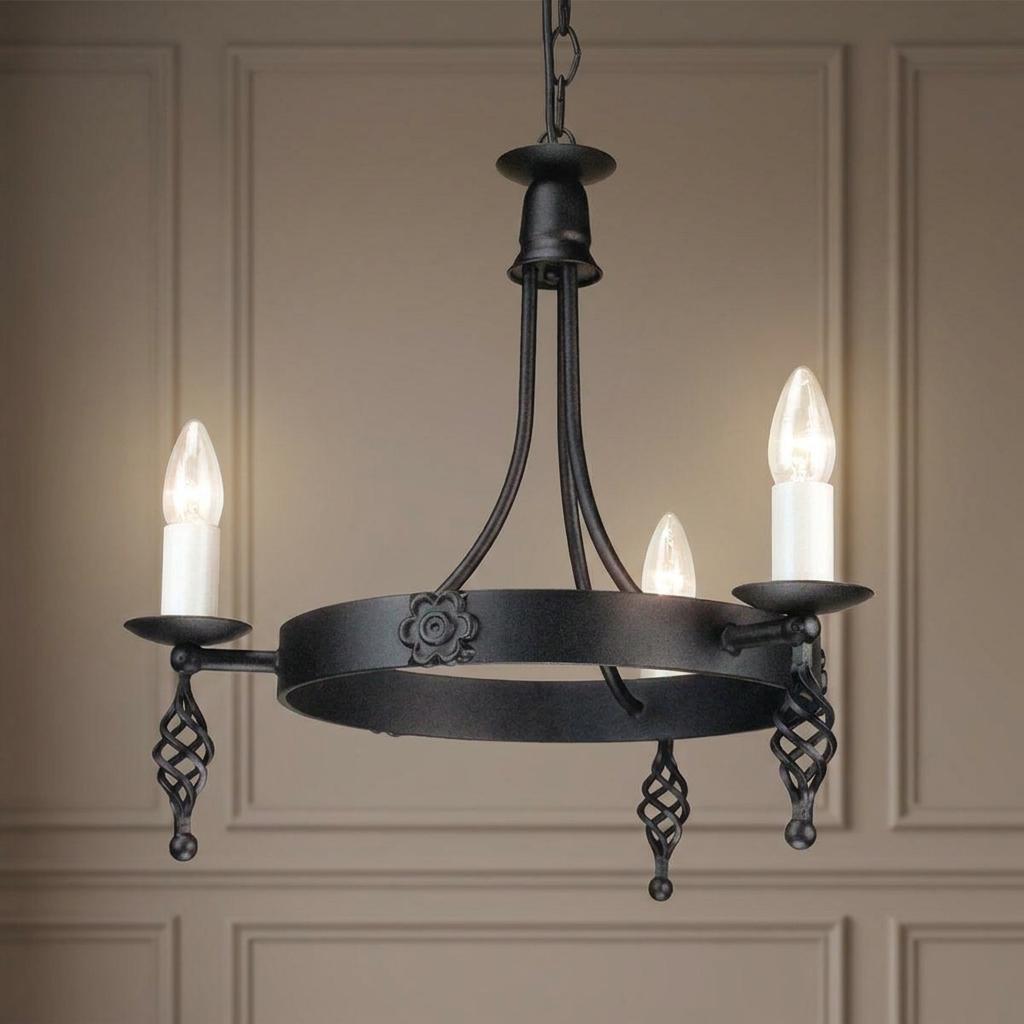 Elstead Belfry three-light black chandelier with lit candle bulbs and wrought iron decorative details.