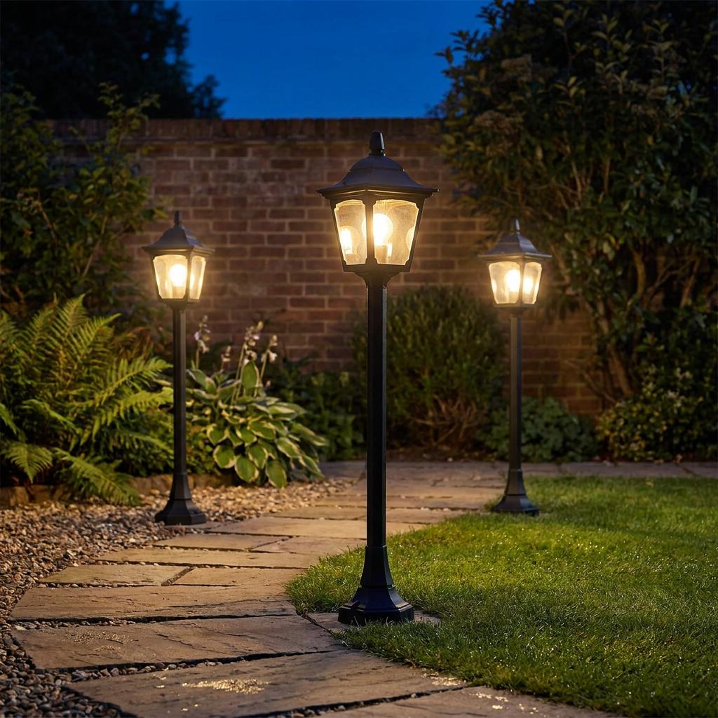 Three black lantern-style outdoor mini bollard lights illuminating a stone garden path at night.