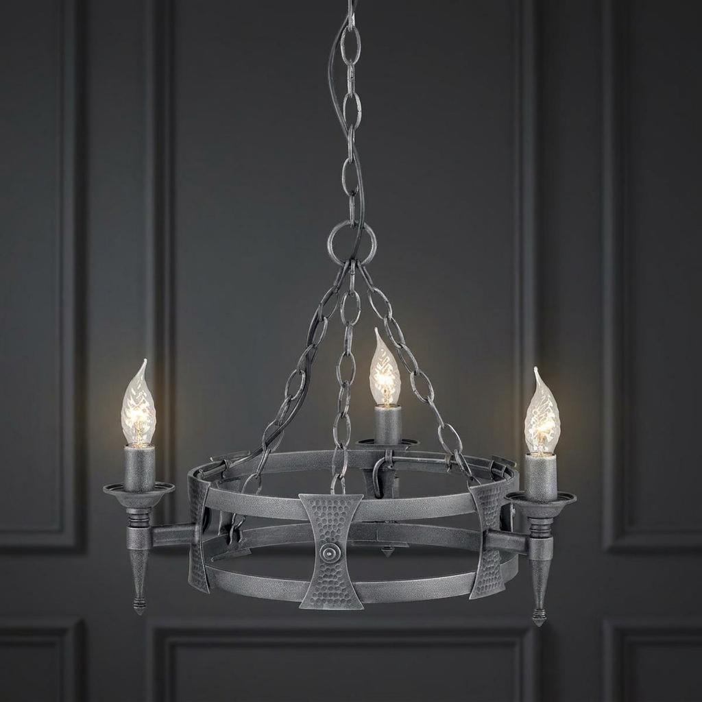 A black and silver 3-light Saxon chandelier with a hand-forged circular frame against a dark paneled wall.