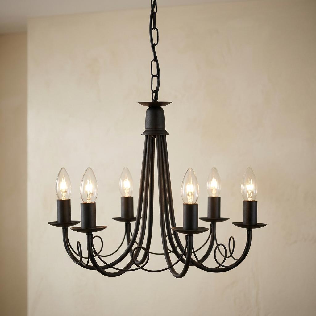A black wrought iron chandelier with six lit candle bulbs hanging from a chain against a neutral wall.