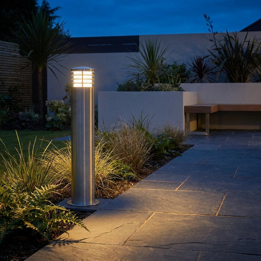 Elstead Sandbanks stainless steel bollard light illuminating a modern garden path with a warm glow at dusk.