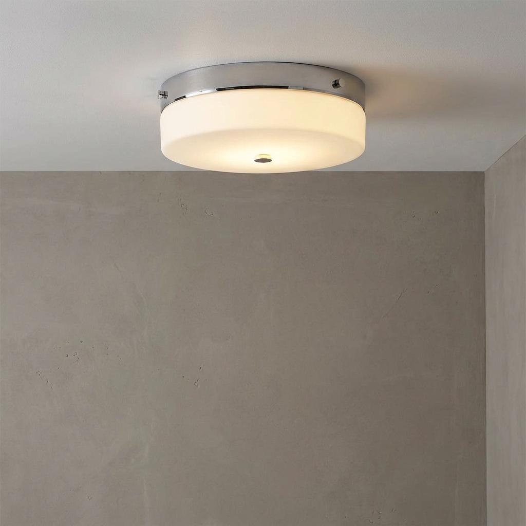 Polished chrome flush-mount bathroom ceiling light with a frosted white glass diffuser on a white ceiling.