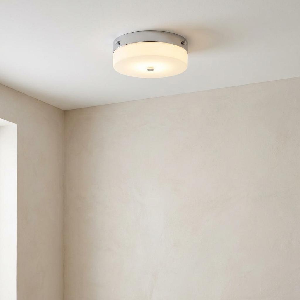 Circular flush mount bathroom light with polished chrome trim and frosted glass diffuser on a white ceiling.