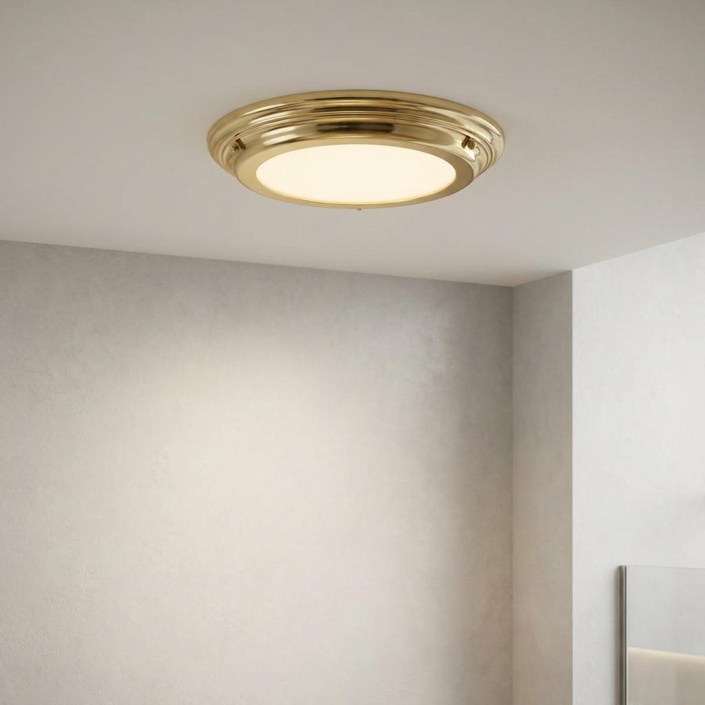 Elstead Welland polished brass flush ceiling light with an opal glass diffuser mounted on a neutral ceiling.
