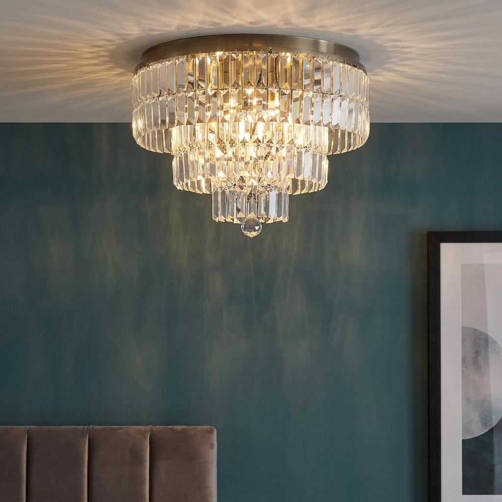 Empire-style crystal chandelier with antique brass trim, illuminated against a dark teal interior wall.