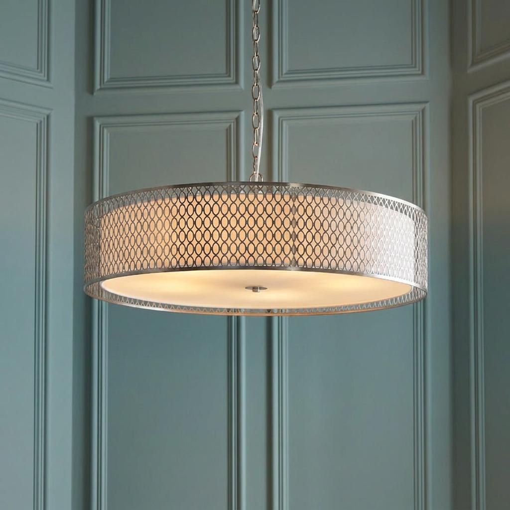 A large satin nickel pendant light with a lattice drum shade and white diffuser against a teal paneled wall.