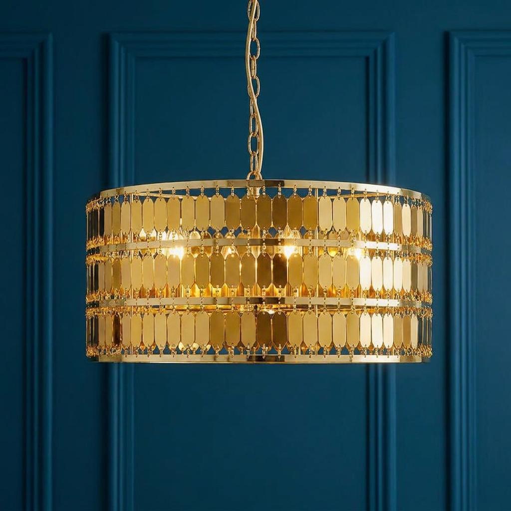 Gold drum-shaped pendant light with tiered metallic oval discs against a navy blue paneled wall.