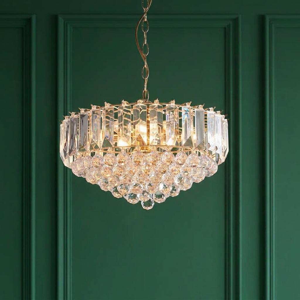Elegant brass and clear acrylic 6-light pendant with cascading prisms against a green paneled wall.