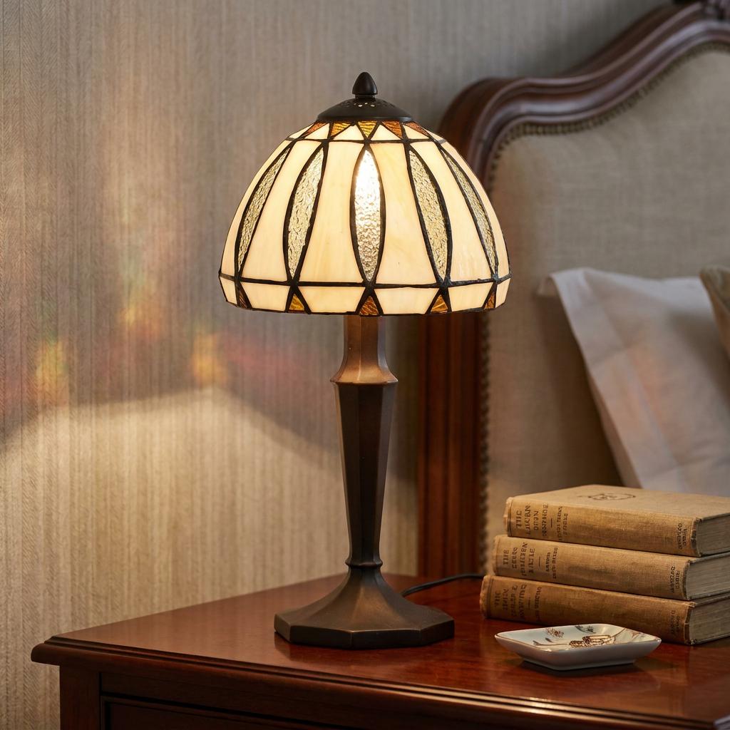 A Farndon Tiffany bedside table lamp with a cream and amber glass shade on a dark wood bedside table.