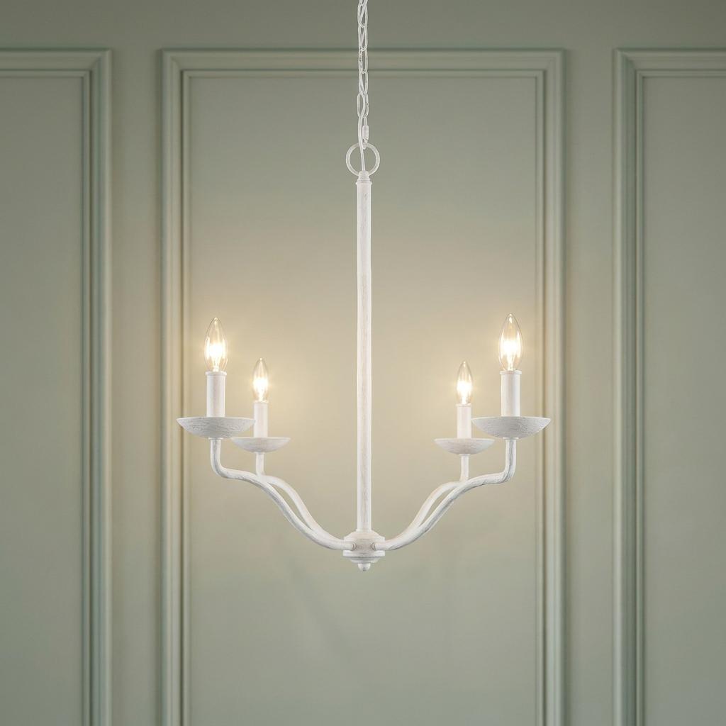 Feiss Annie 4 light white chandelier with lit candle bulbs and curved arms against a paneled green wall.