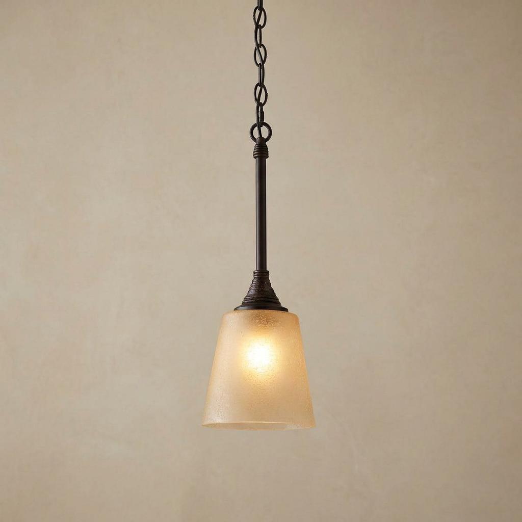 Feiss Arbor Creek bronze mini pendant light with a tapered frosted amber glass shade hanging from a chain.