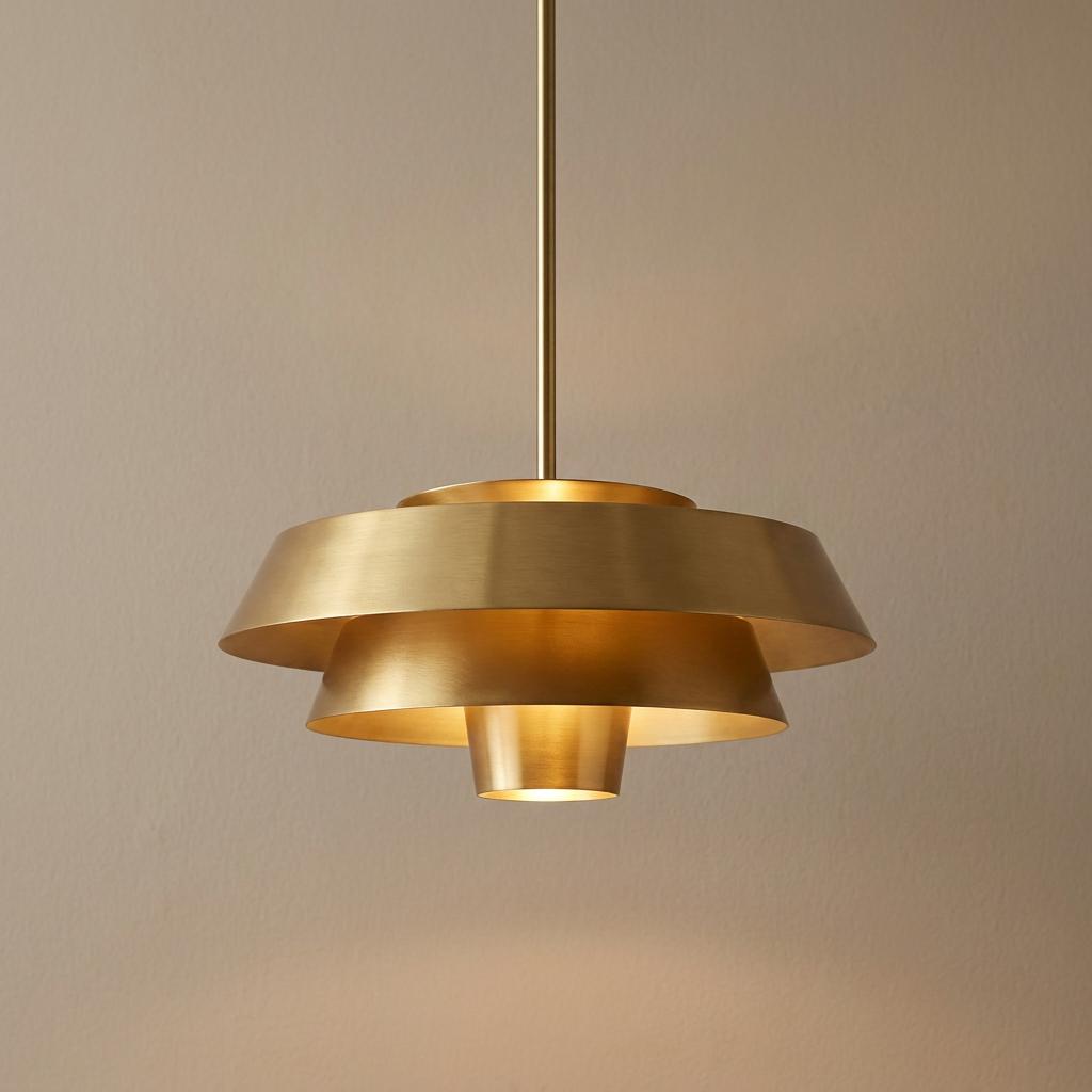 Feiss Brisbin burnished brass tiered ceiling pendant light hanging against a neutral beige wall.