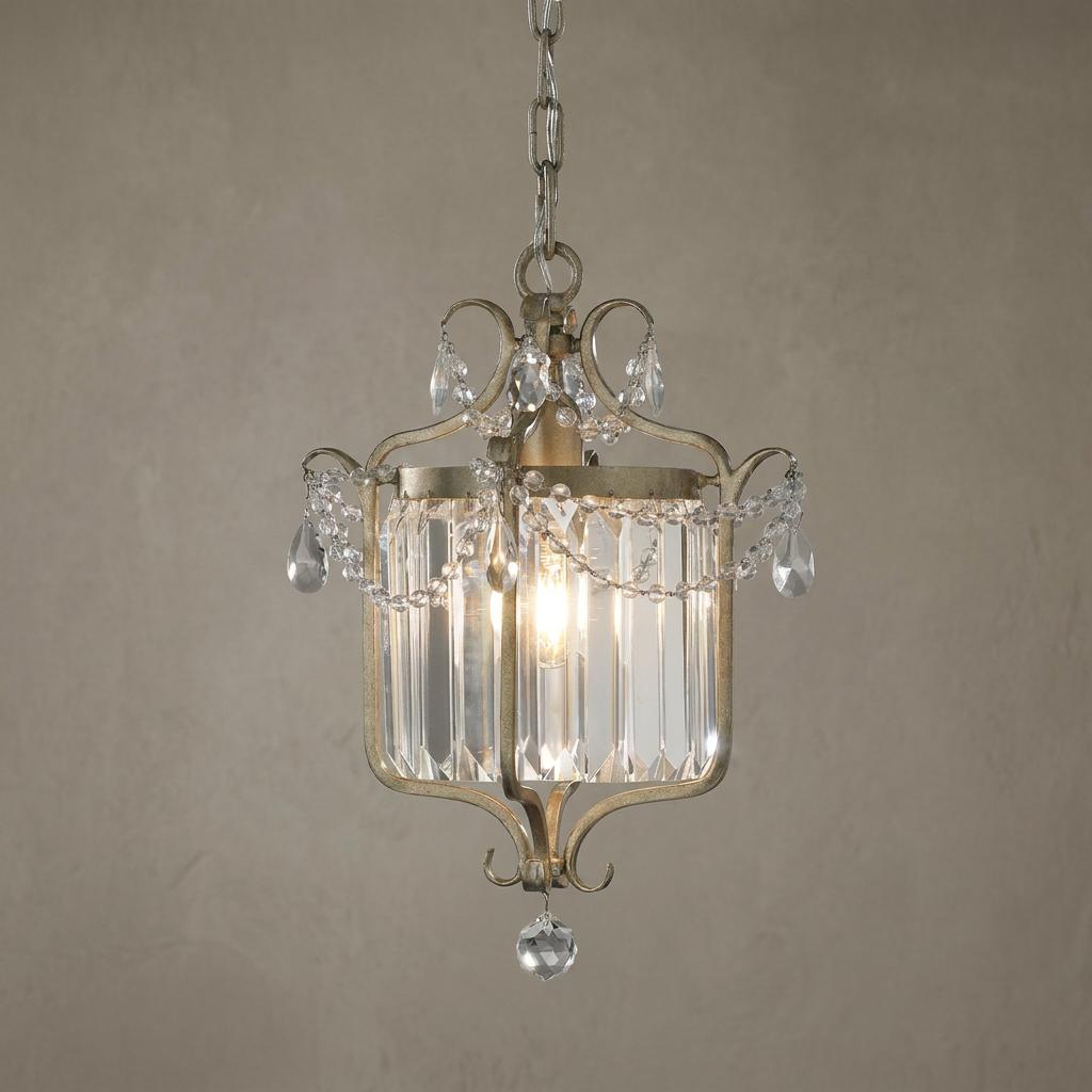 Ornate silver-leaf lantern featuring vertical glass panels and decorative crystal swags against a neutral wall.