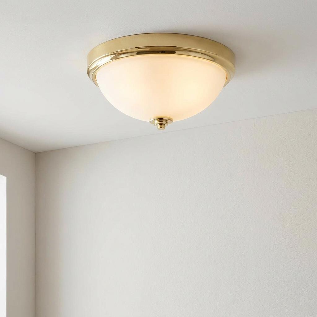 Traditional polished brass flush mount ceiling light featuring a frosted glass dome on a plain white ceiling.