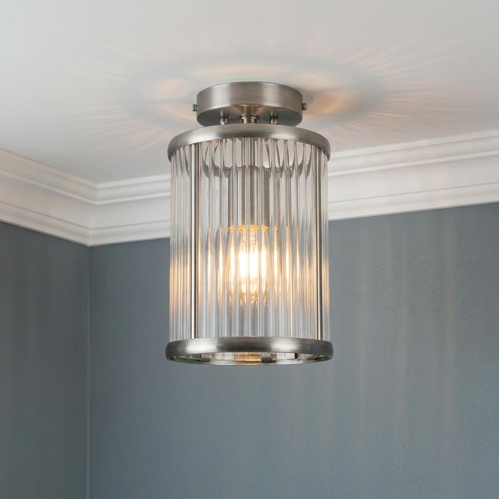 Fern Antique Chrome flush light with a cylindrical ribbed glass shade glowing against a blue wall.