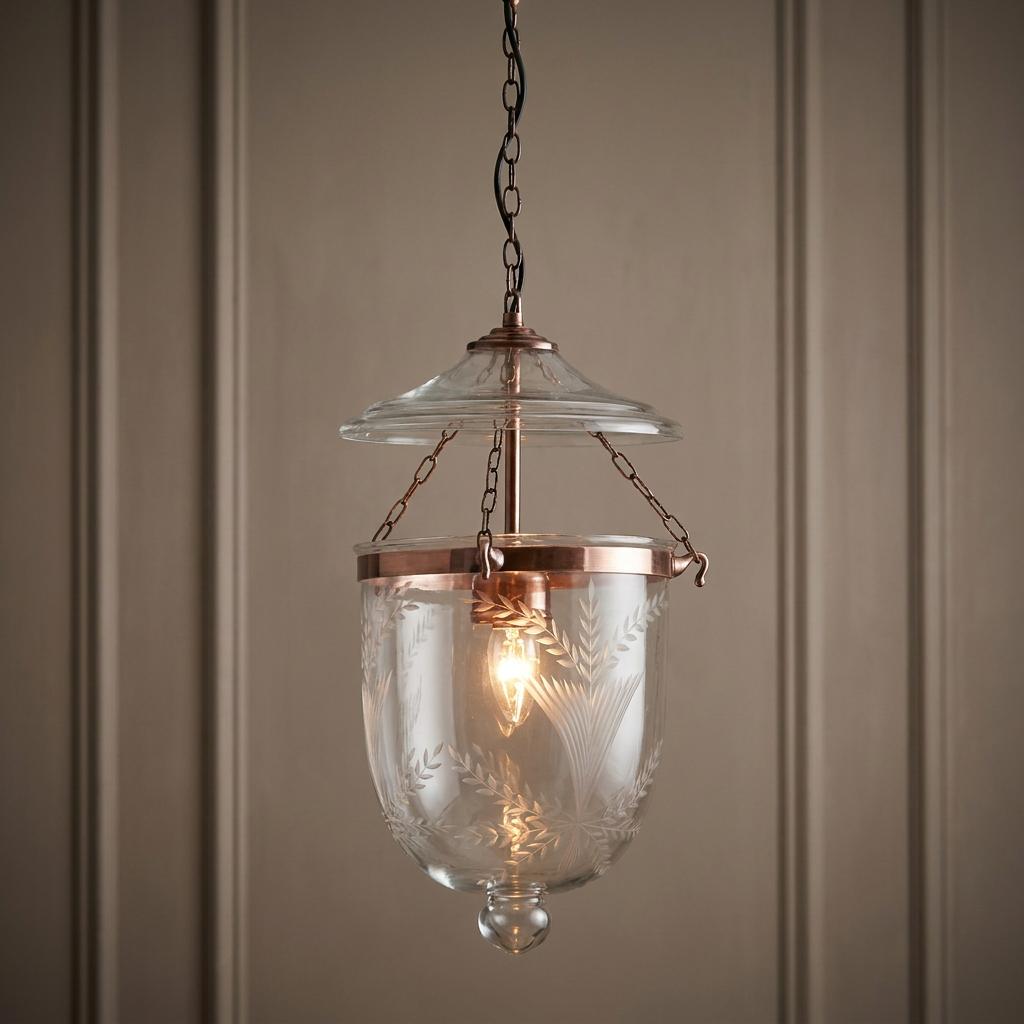 Copper and etched glass Georgian lantern light fixture hanging from a chain in front of a paneled wall.