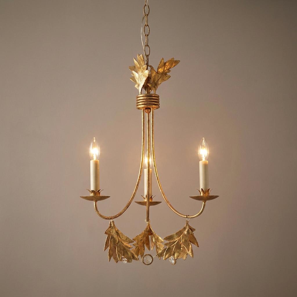 Three-light gilded gold chandelier featuring botanical leaf accents and candle-style bulbs.