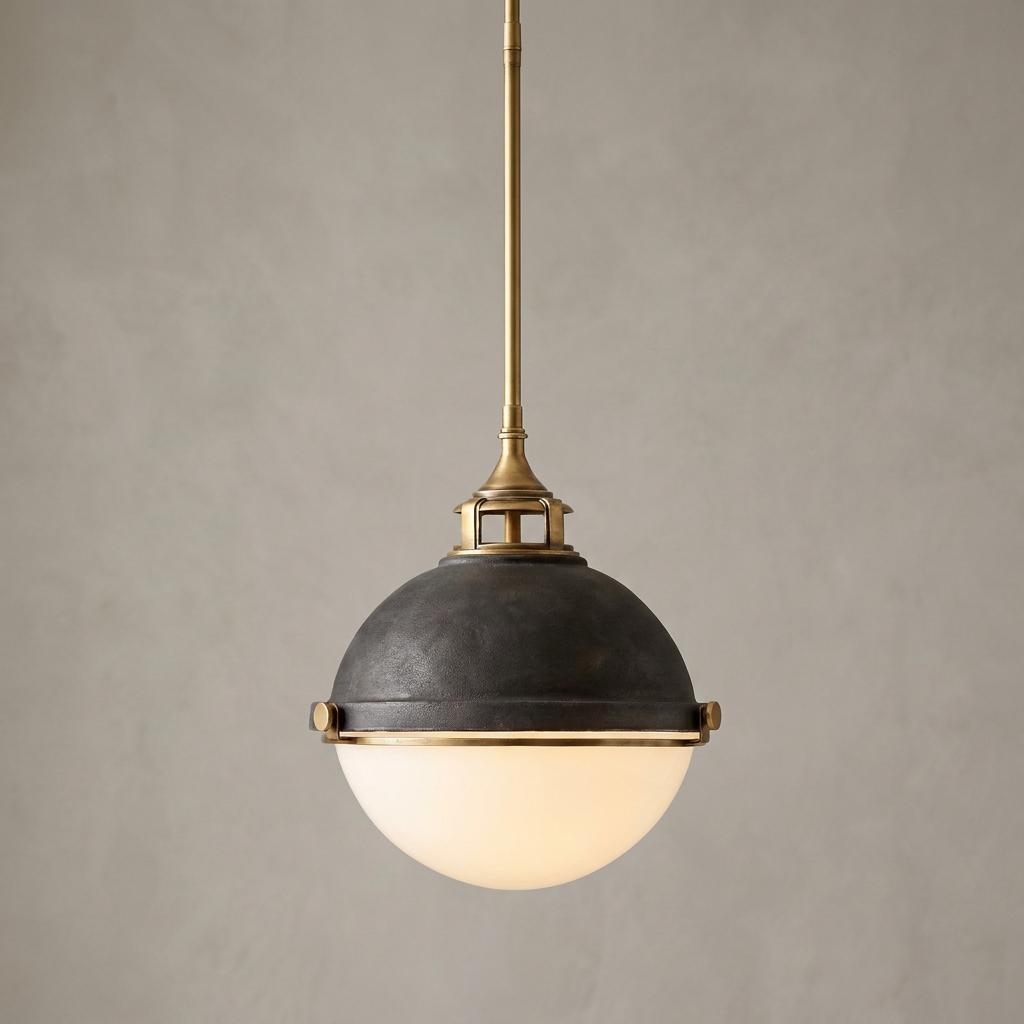 Industrial pendant light with a dark zinc dome, brass hardware, and a glowing white opal glass globe.