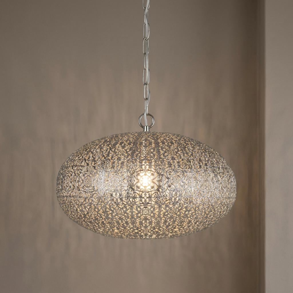 Intricate nickel fretwork pendant light with an oval shade hanging from a chain against a neutral wall.
