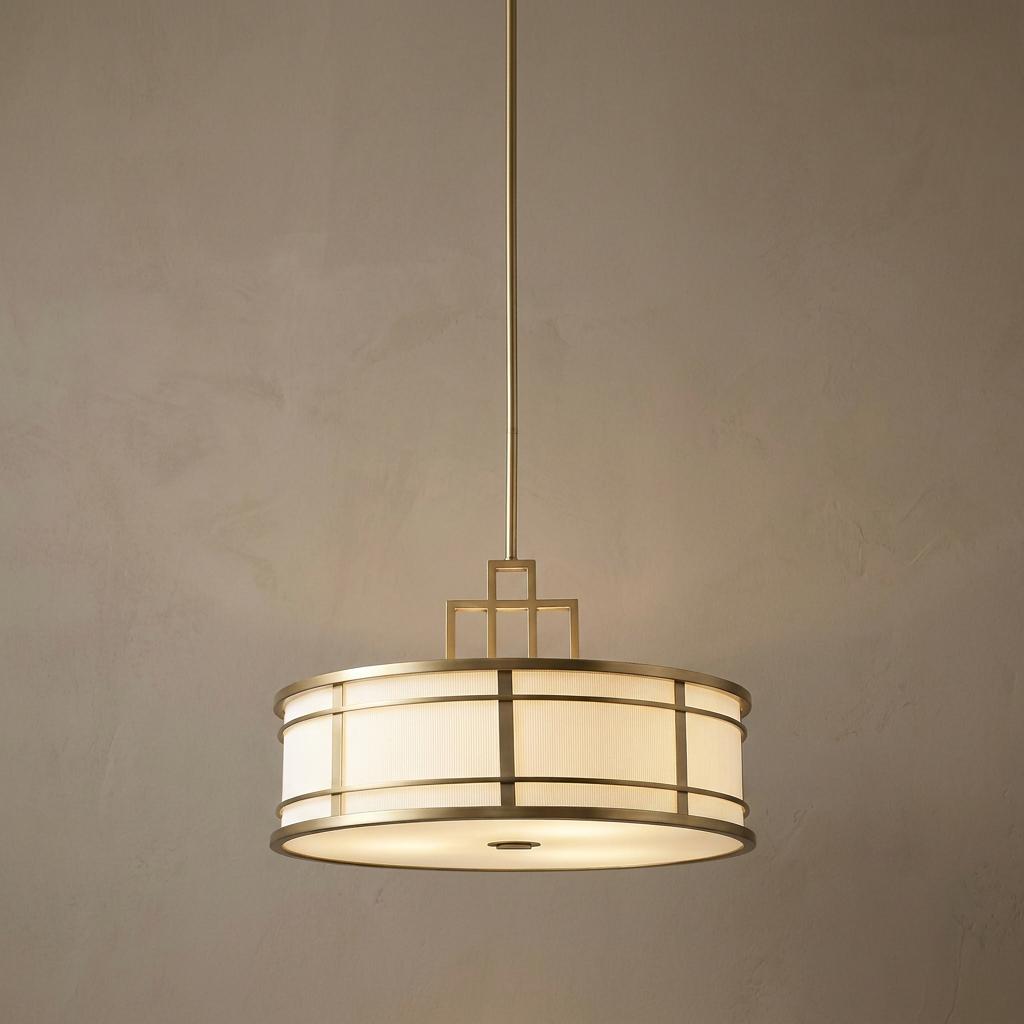 Fusion Large Art Deco ceiling pendant with a brass geometric drum shade and warm diffused light against a tan wall.