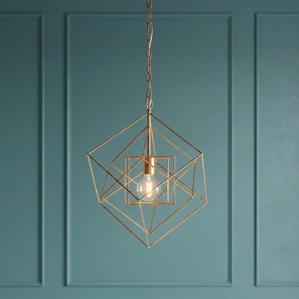 Gold leaf geometric pendant light featuring nested wire frames and an exposed bulb against a teal paneled wall.