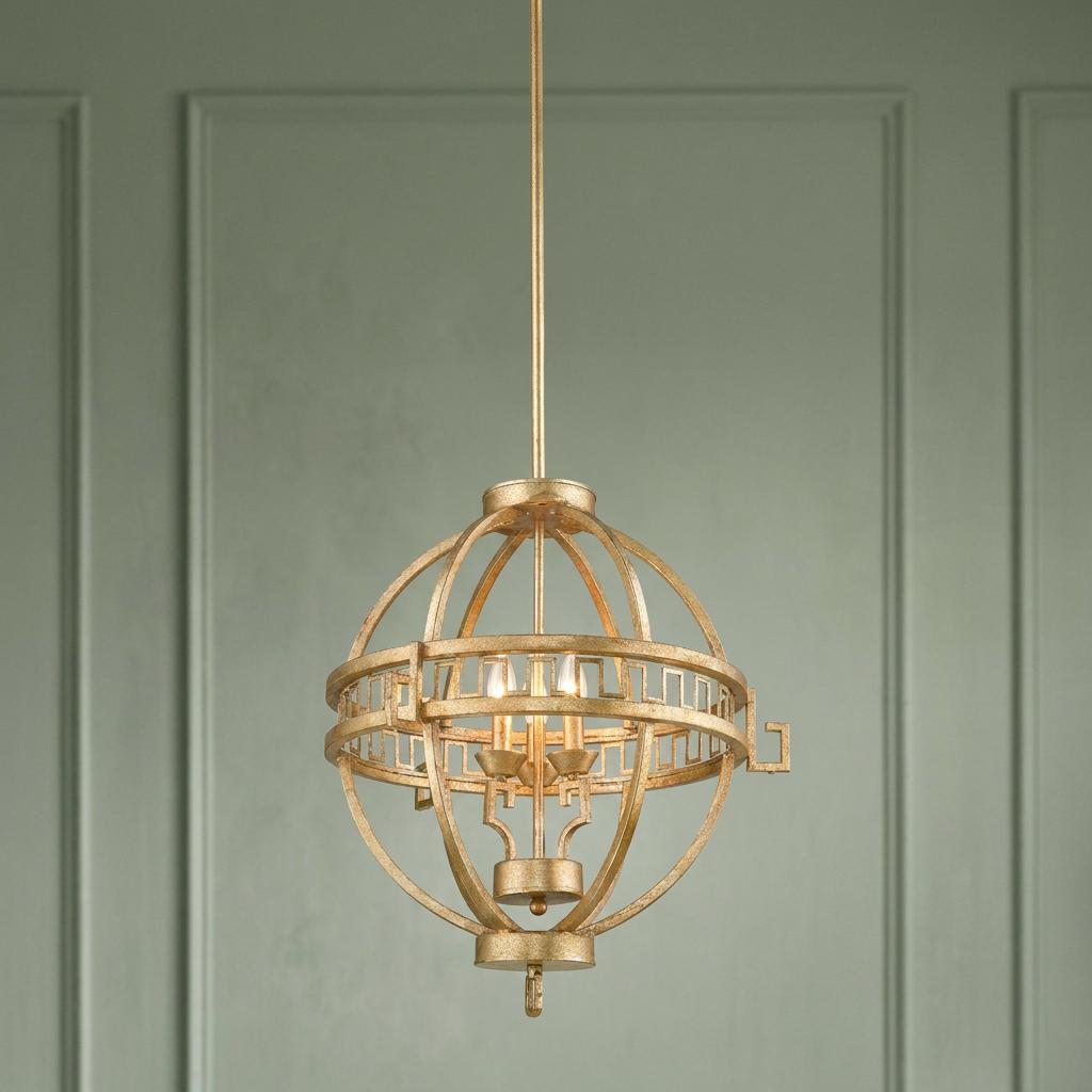 Three-light gold armillary globe pendant chandelier with Greek key detailing against a sage green paneled wall.