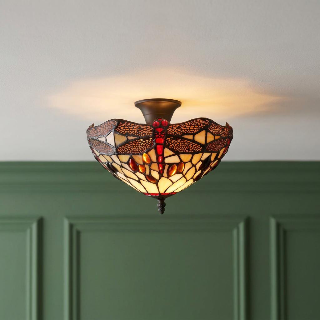 Golden dragonfly semi-flush Tiffany ceiling light illuminated against a white ceiling and green paneled wall.