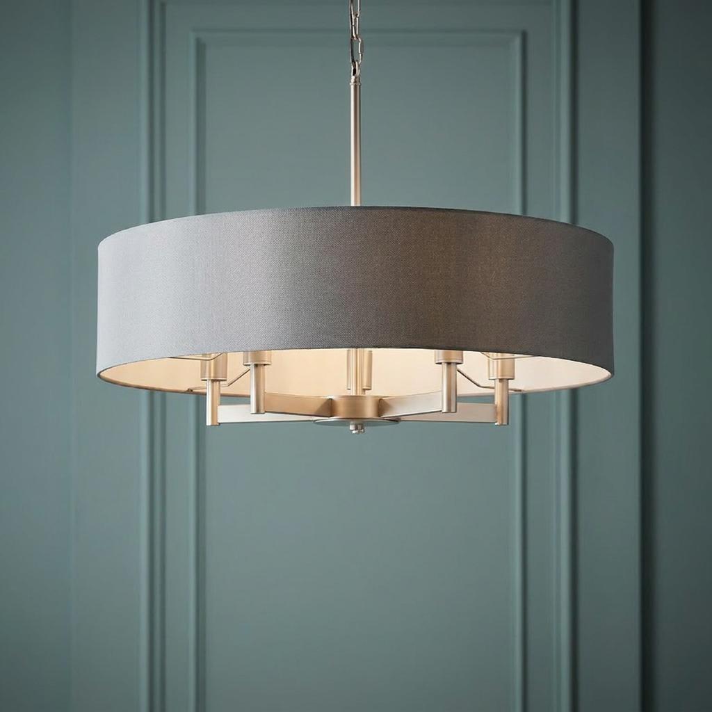 Modern nickel five-light pendant with a grey fabric drum shade against a teal paneled background.