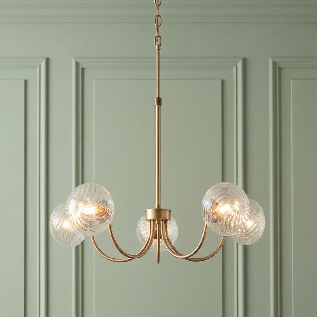Brass five-light pendant with swirled glass globes against a light green paneled wall.