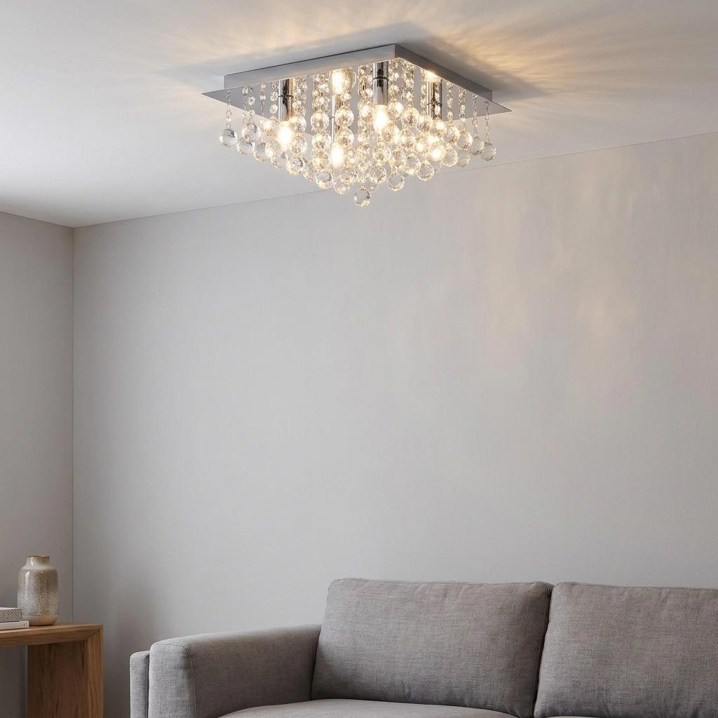 Square chrome ceiling light with crystal droplets illuminated in a modern living room above a grey sofa.