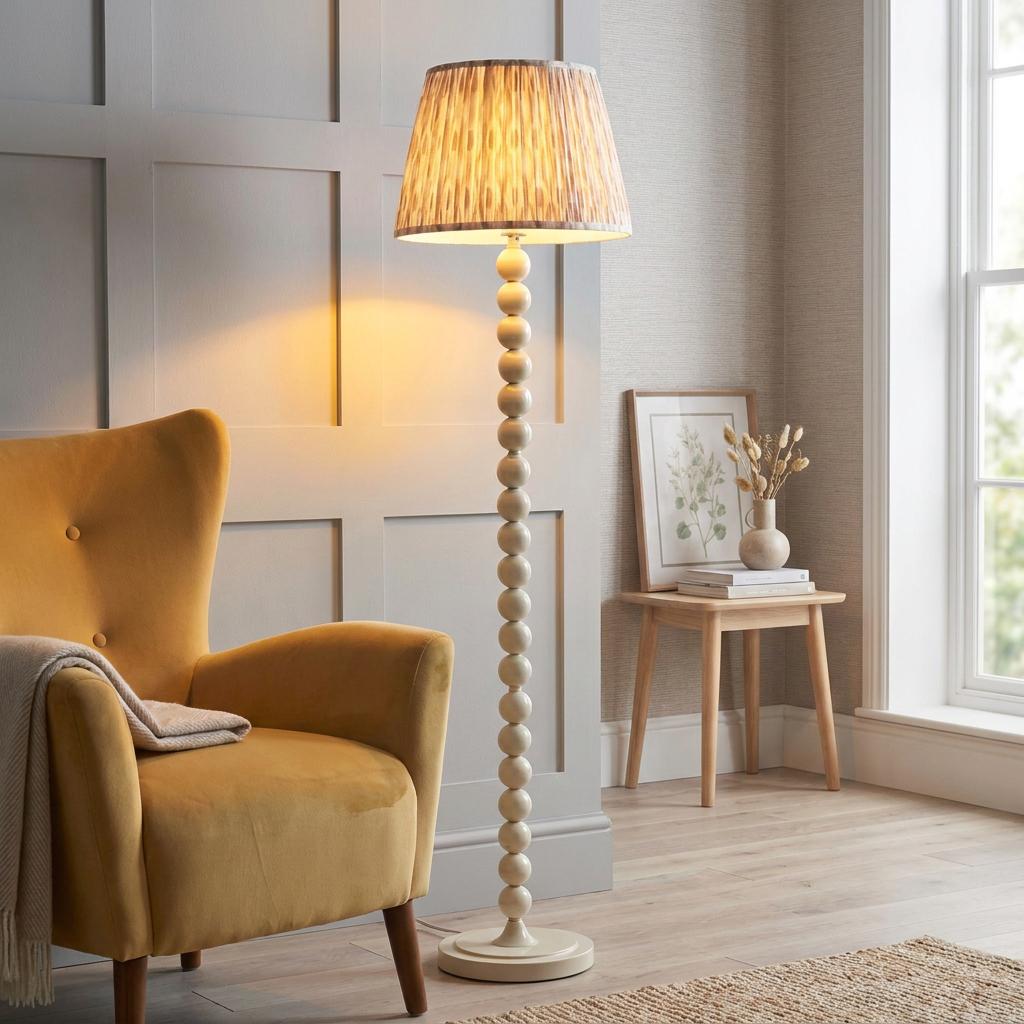 Almond white floor lamp with a beaded base and Ikat shade next to a yellow armchair in a living room.