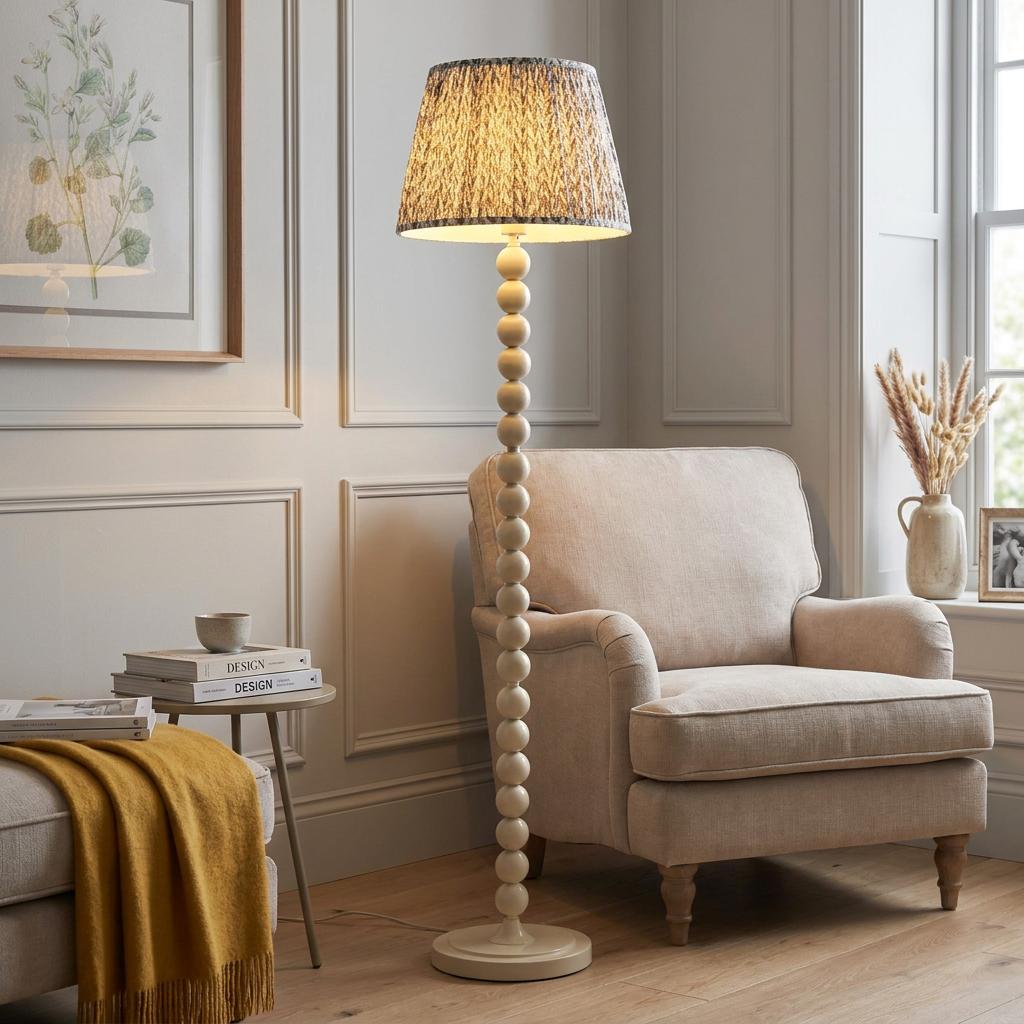 Higgledy almond white floor lamp with a pearl grey leaf pattern shade next to a beige armchair in a living room.