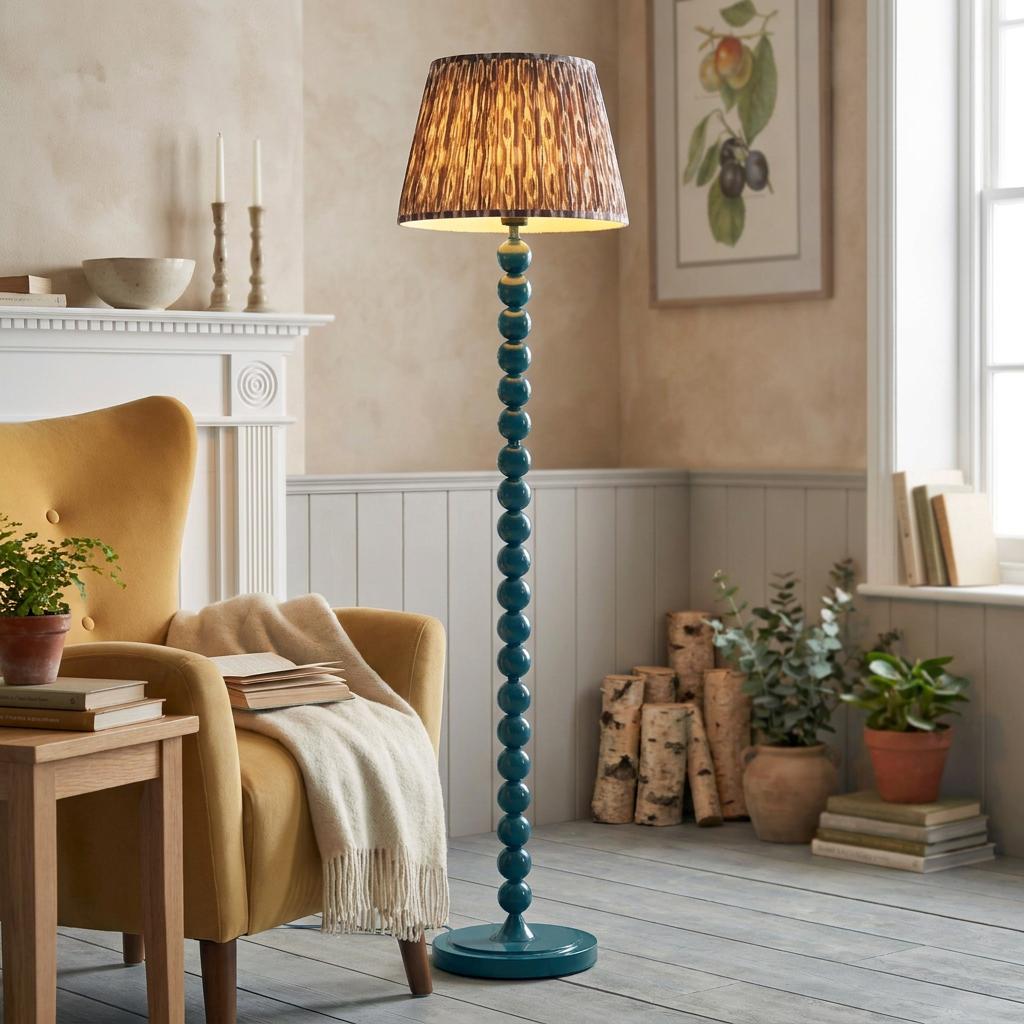 Blue beaded floor lamp with a patterned grey shade beside a yellow armchair in a cozy living room.
