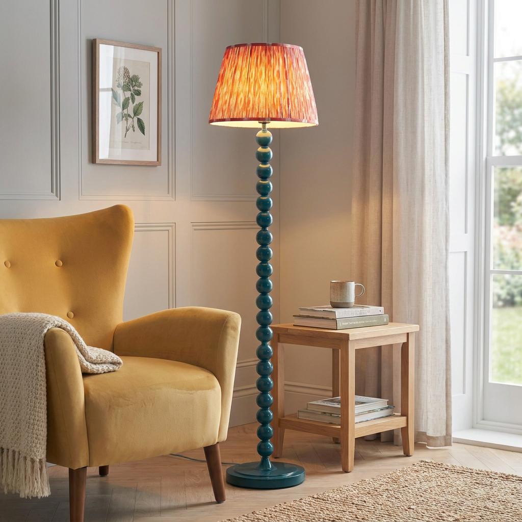 Blue bobbin floor lamp with a coral pink Ikat shade standing in a living room beside a yellow wingback chair.