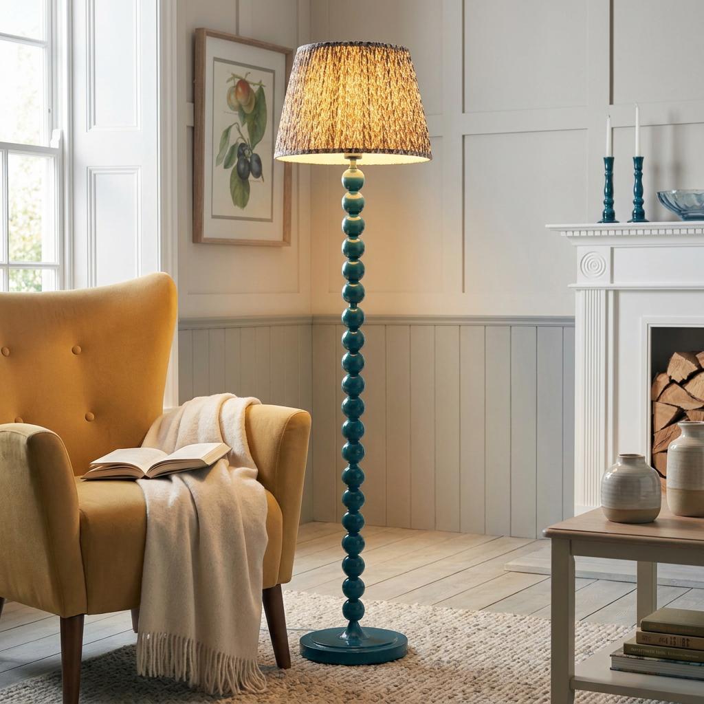 Blue bobbin floor lamp with a patterned pearl grey shade stands by a yellow armchair in a cozy living room setting.