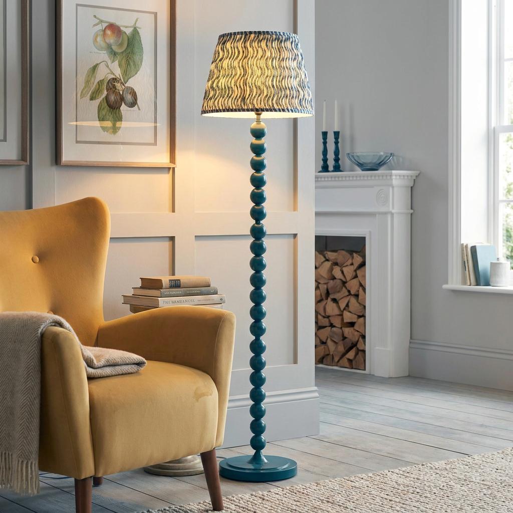 Teal bobbin floor lamp with a blue rippled shade stands next to a yellow armchair in a cozy living room.