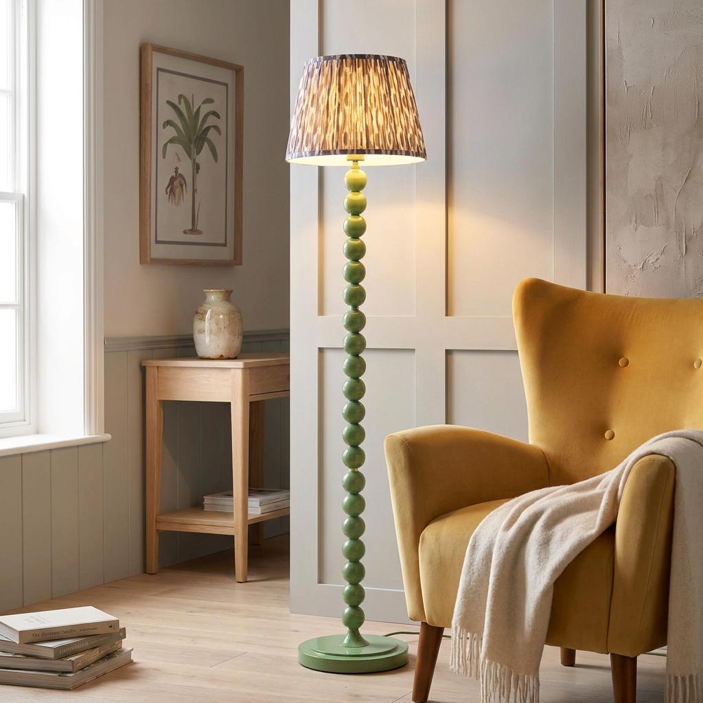 Green bobbin floor lamp with an ikat pattern shade next to a yellow armchair in a cozy living room.