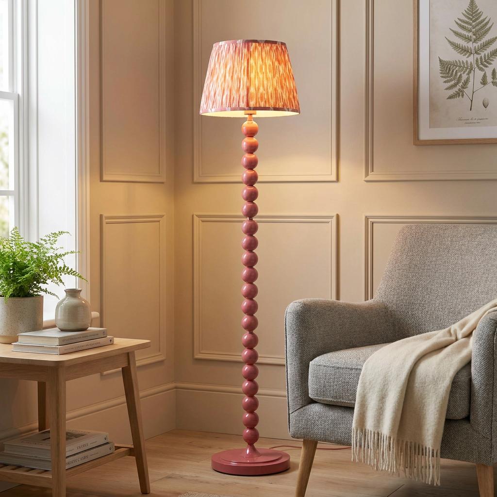 Higgledy pink floor lamp with a beaded base and ikat shade illuminating a living room corner by an armchair.